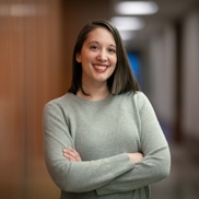 A woman with brown hair wears a light green sweater and has crossed arms
